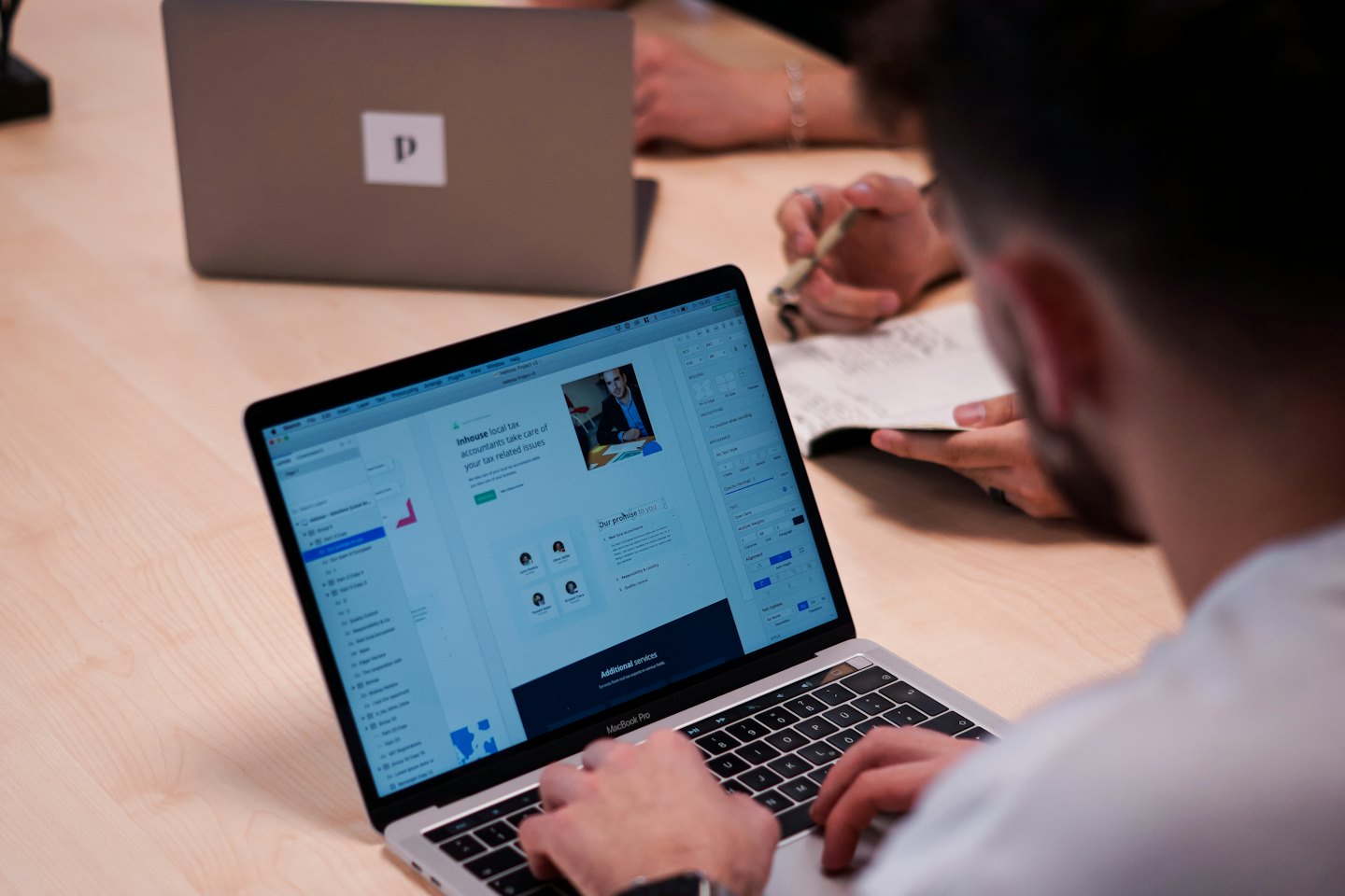 Mani che digitano su un laptop che mostra il design di un sito web.