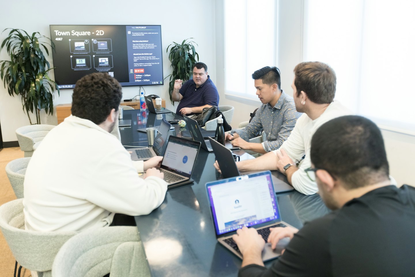 Professionisti diversi collaborano attorno a un tavolo da conferenza in un ufficio moderno.